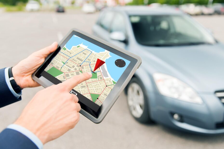 Mãos utilizando tablete com GPS frente ao carro